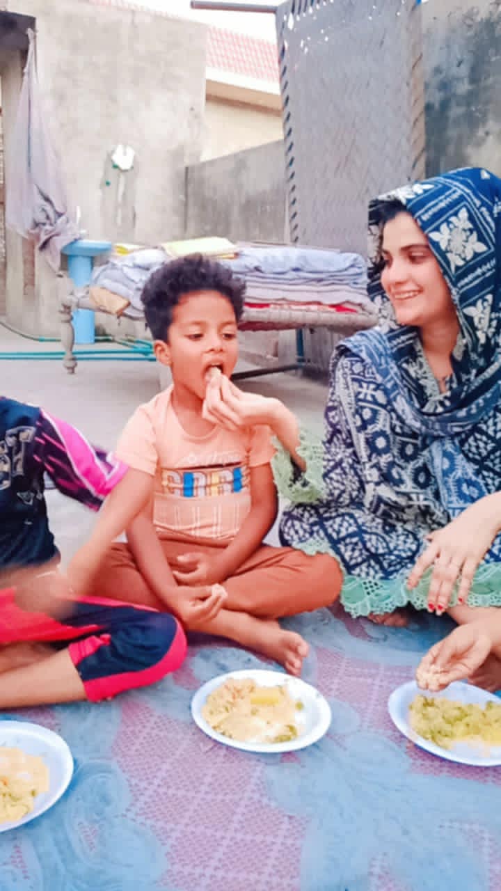 Children sitting on a mat with plates of food.