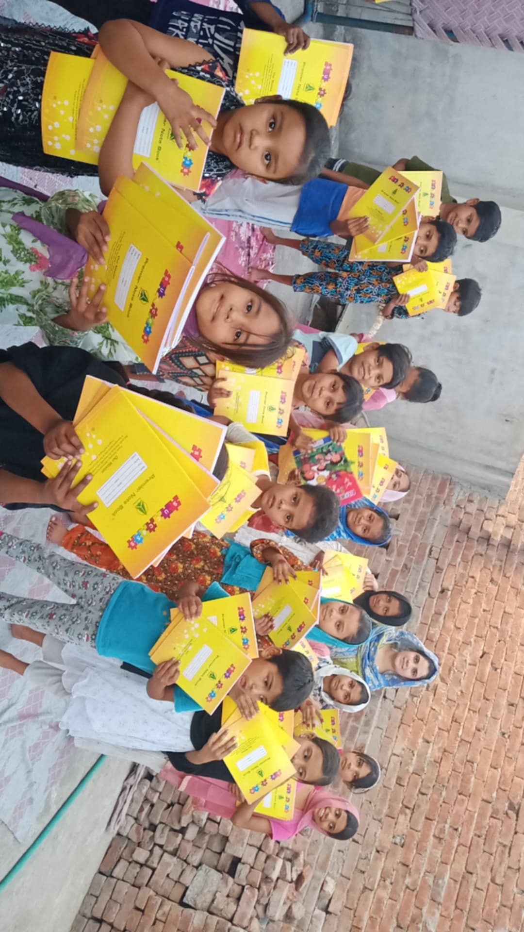 A group of children holding yellow school notebooks.