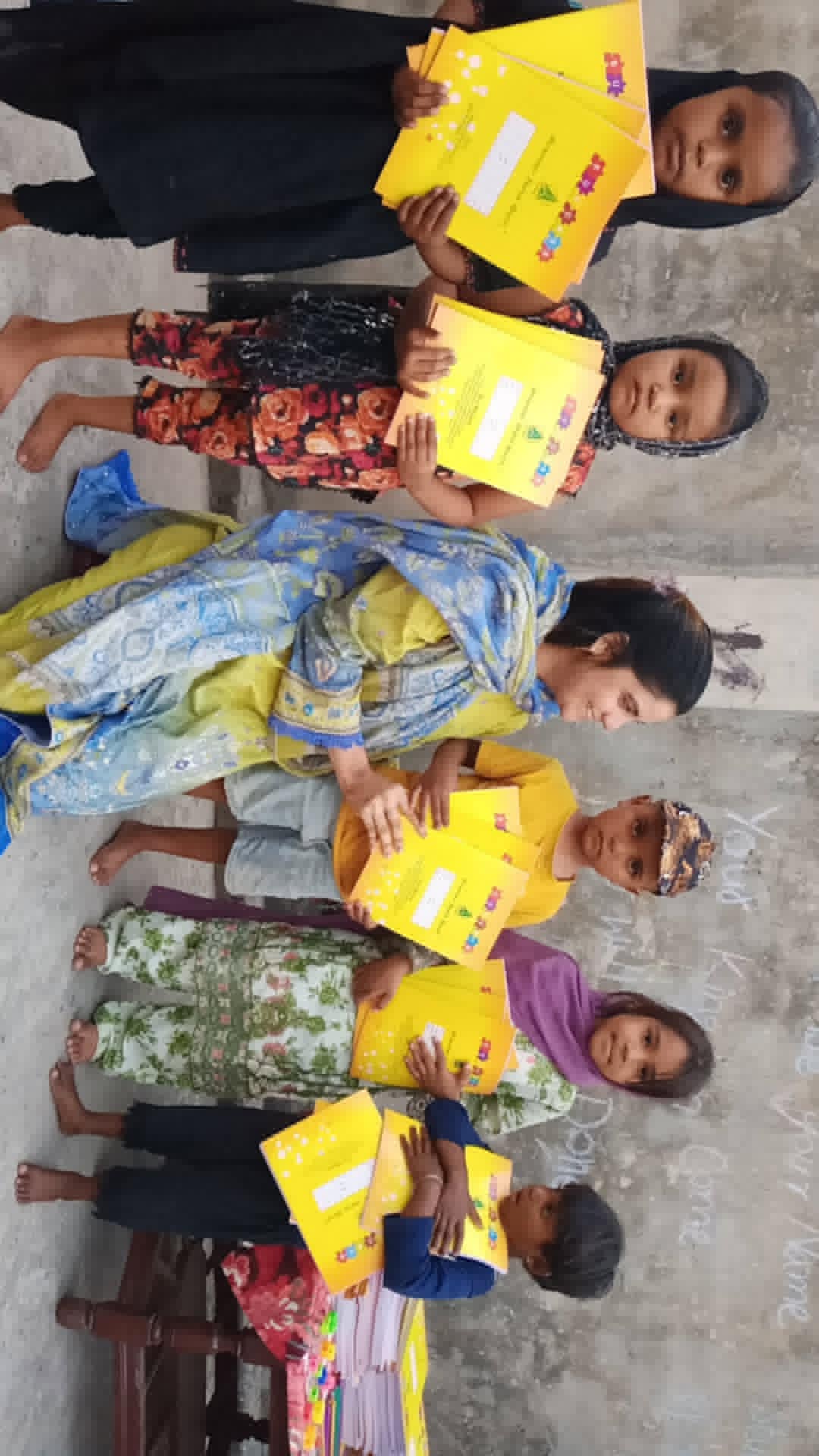 Children standing with newly received yellow notebooks.